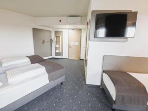 ein Hotelzimmer mit 2 Betten und einem Flachbild-TV in der Unterkunft B&B HOTEL Wiener Neudorf in Wiener Neudorf