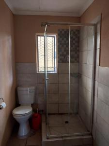 a bathroom with a shower with a toilet and a window at The Grace quest house in Ngodini