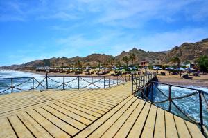 a wooden pier with chairs and umbrellas on a beach at Tropitel Dahab Oasis in Dahab
