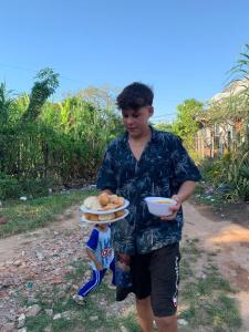 een jongen met een bord brood en een kom eten bij NLCO Homestay in Siem Reap