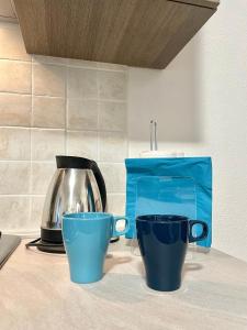 two blue cups sitting on a counter with a tea kettle at CASA GIULIA - Holiday Home in Olbia