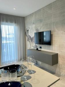 einen Tisch mit Weingläsern und einen TV an der Wand in der Unterkunft Rondinella Suite in Lignano Sabbiadoro