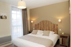 a bedroom with a large white bed with a wooden headboard at Hôtel Restaurant Corto Maltese in Le Palais