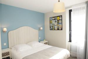 a bedroom with a white bed and a blue wall at Hôtel Restaurant Corto Maltese in Le Palais