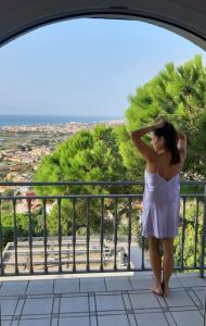 una donna in abito bianco in piedi su un balcone di Villa con piscina privada climatizada 29ºC a Santa Susanna