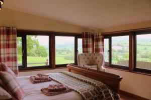 a bedroom with a bed with a chair and windows at The Retreat in Llanrhaeadr-ym-Mochnant
