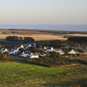 a group of houses in a field next to the ocean at Hôtel Restaurant Corto Maltese in Le Palais