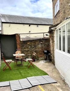 a patio with chairs and a table and a grill at A beautiful studio flat with garden in London