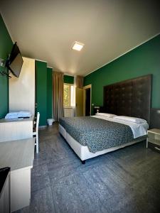 a bedroom with a large bed and a green wall at Albergo Italia in Porto Tolle