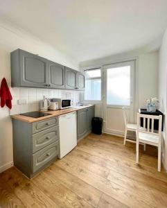 a kitchen with gray cabinets and a wooden floor at A beautiful studio flat with garden in London