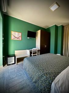 a hotel room with a bed and a green wall at Albergo Italia in Porto Tolle