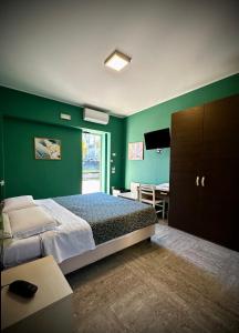 Albergo Italia في بورتو تولي: غرفة نوم بجدران خضراء وسرير وطاولة