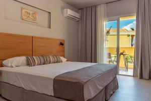 a bedroom with a large bed and a balcony at Olympion Village in Kavos