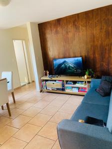 uma sala de estar com um sofá azul e uma televisão em Felicitatem Apartments Higienópolis - Apartamento Compartilhado em São Paulo