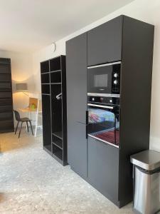 eine schwarze Küche mit einer Mikrowelle und einem Backofen in der Unterkunft Central Studio in Kortrijk in Kortrijk