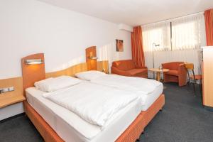 ein Schlafzimmer mit einem großen weißen Bett und einem Stuhl in der Unterkunft Tespo Hotel und Sportpark in Kaarst
