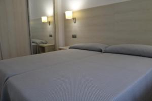 um quarto com uma cama com lençóis azuis e um espelho em MyF Michelangelo sun em Salou