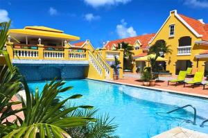 a pool in front of a yellow house at Amsterdam Manor Beach Resort in Palm-Eagle Beach