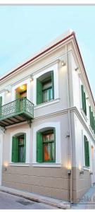 - un bâtiment blanc avec des portes et des fenêtres vertes dans l'établissement Atsiki's 54 apartments, à Chios