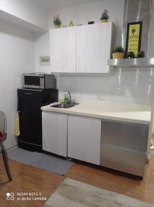 a kitchen with white cabinets and a black refrigerator at Azure Place in Manila