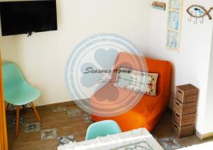 Habitación con sillón naranja y ventilador. en Seasons Home San Foca en San Foca