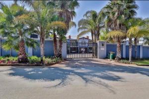 a gate with palm trees in front of a house at Honeymoon suite in Schoemansville in Hartbeespoort