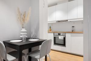 una cocina blanca con mesa negra y sillas en 5min to Bryggen - Renovated - Budget friendly, en Bergen
