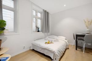 a white bedroom with a bed and a desk at 5min to Bryggen - Renovated - Budget friendly in Bergen