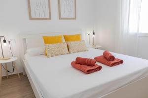 białe łóżko z 2 pomarańczowymi poduszkami w obiekcie Sol y Mar Boutique Apartments w Alicante