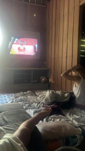 a person laying on a bed watching a tv at Camping rustico recanto do combatente in Manaus