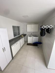 uma pequena cozinha com armários brancos e electrodomésticos brancos em Casa Ceci SUÍTES/QUARTOS em São Paulo