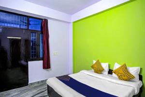 a bedroom with a green wall and a bed with yellow pillows at SPOT ON Raj Hotel Vip Near Worlds Of Wonder in Kalkaji Devi