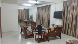 a living room with wooden chairs and a television at Happy homestay in Teluk Intan