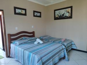 a bedroom with two beds and two pictures on the wall at Pousada Bem-te-vi in Aracaju