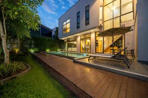 a house with a wooden deck with a bench and an umbrella at Serene Wallaya Villa Harmony in Ban Pak Lak