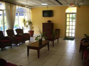 uma sala de espera com cadeiras e uma televisão na parede em Royal Islander Hotel em Freeport