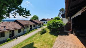 vistas a una fila de casas con terraza de madera en Lechbruck am See Feriendorf Hochbergle Haus 131, en Lechbruck