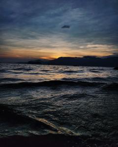 a sunset on the beach with the ocean at Casa temporada Ilhabela in Ilhabela