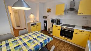 una cocina con armarios amarillos y una mesa en una habitación en Bei München Ferienwohnung in Grafrath "Amperland", en Grafrath