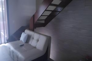 uma sala de estar com um sofá branco e uma escada em Apartamentos em SC em Itajaí