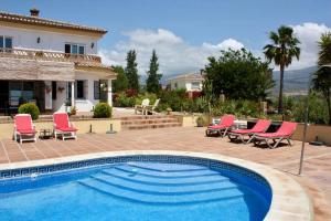 een zwembad met stoelen en een huis bij Casa nuestro sueño in Viñuela