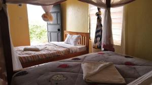two beds in a bedroom with a window at Tausa Tsavo Eco Lodge in Voi