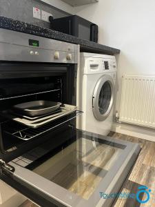 a kitchen with an oven and a washing machine at Beautiful Bungalow for solo and couple travellers in Sheldon