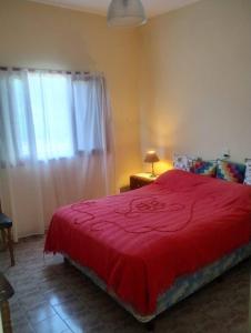 1 dormitorio con cama roja y ventana en Encantadora Casa con parque en La Falda