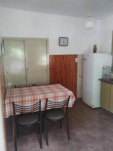 a kitchen with a table with chairs and a refrigerator at Encantadora Casa con parque in La Falda