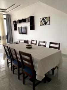 a dining room table with a white tablecloth and chairs at Maison Come and See Burundi Village A in Bujumbura