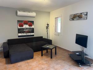 ein Wohnzimmer mit einem schwarzen Sofa und einem TV in der Unterkunft A casa nostra in Biguglia