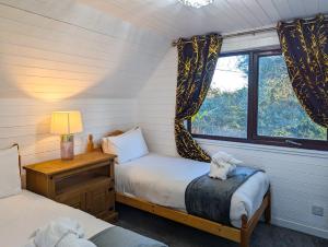 1 dormitorio con 2 camas y ventana en Morrigan 7-Hot Tub-Pet Friendly-Boutique-Perthshire-Families en Perth