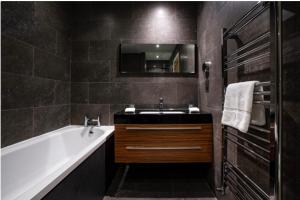 y baño con bañera, lavabo y espejo. en Yewfield Self Catering Apartments en Hawkshead