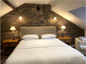 a bedroom with a large white bed with two lamps at Yewfield Self Catering Apartments in Hawkshead